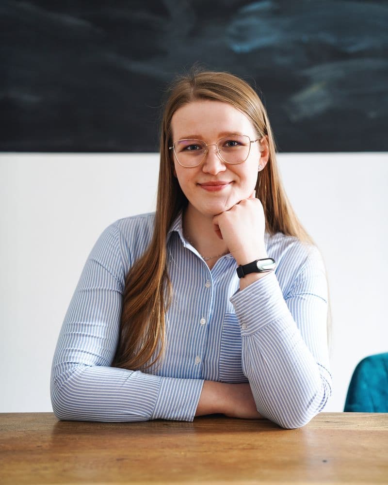 Monika Bzdyk of Krakspire at a wooden table, chin resting on her hand